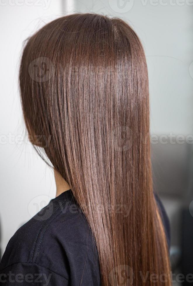 A straight healthy brunette hair that has undergone the hair straightening procedure. straight, shiny and healthy brunette hair photo