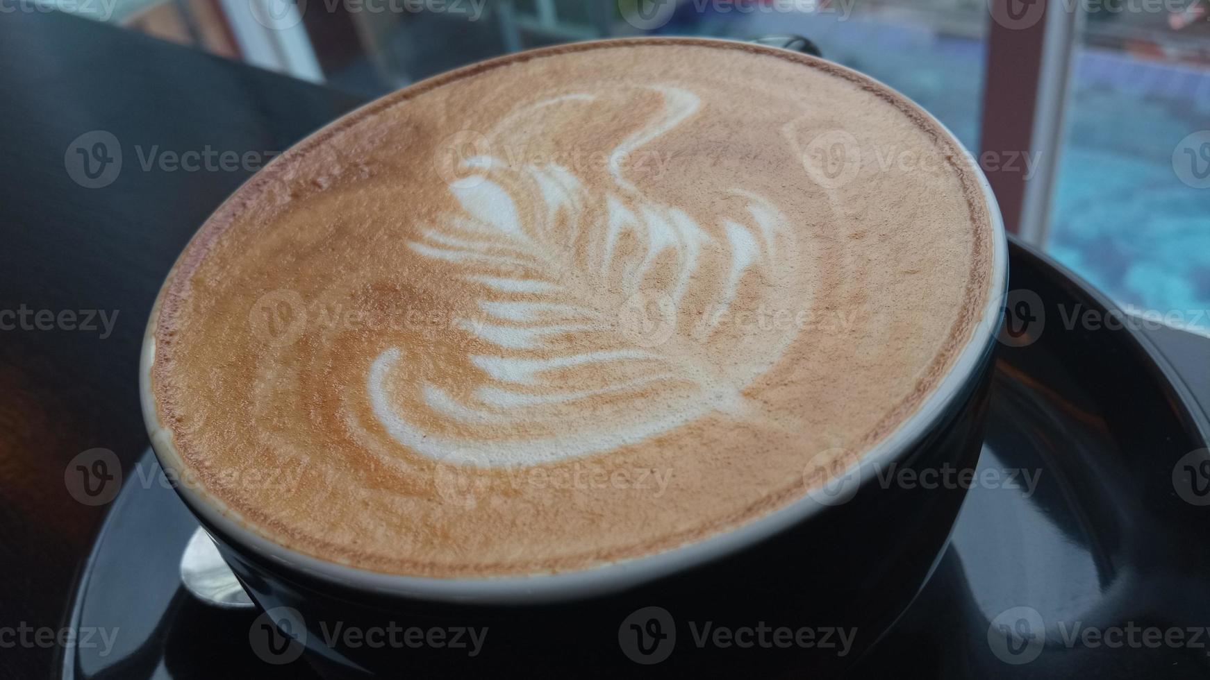 close up shot of capuchino art in a black coffee cup photo