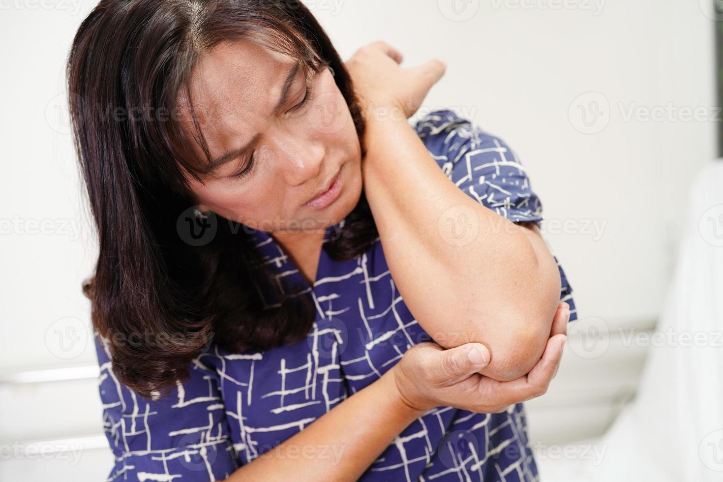 anciana asiática con soporte elástico en el codo para reducir el dolor. foto