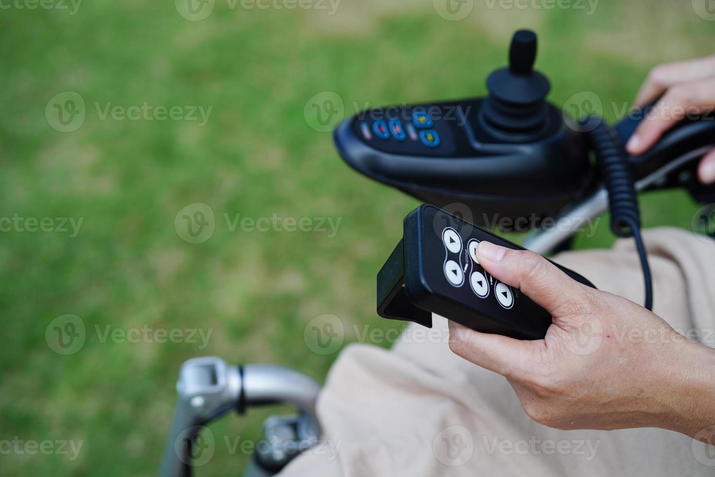Asian elderly woman disability patient sitting on electric wheelchair in park, medical concept. photo
