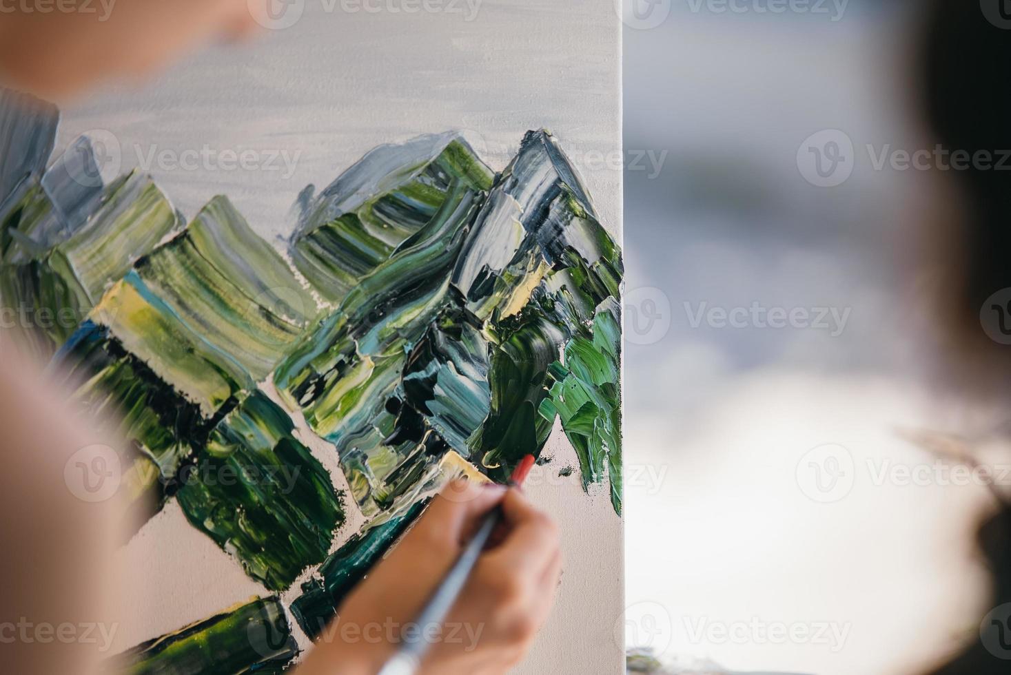 Young woman artist paints with a spatula on the canvas photo