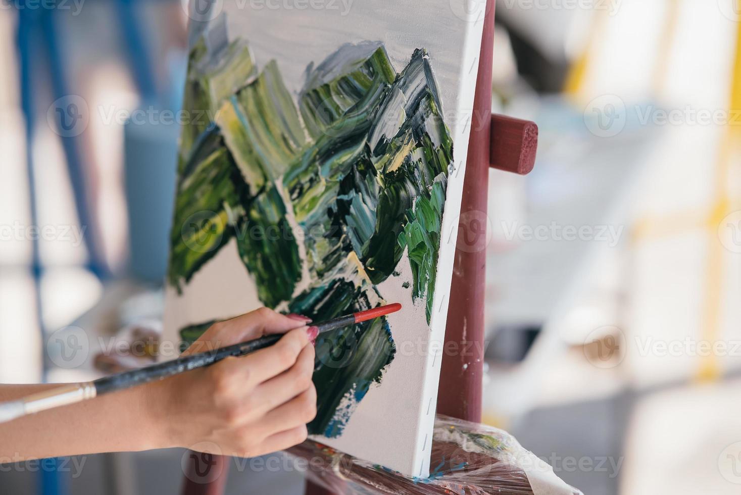 Young woman artist paints with a spatula on the canvas photo