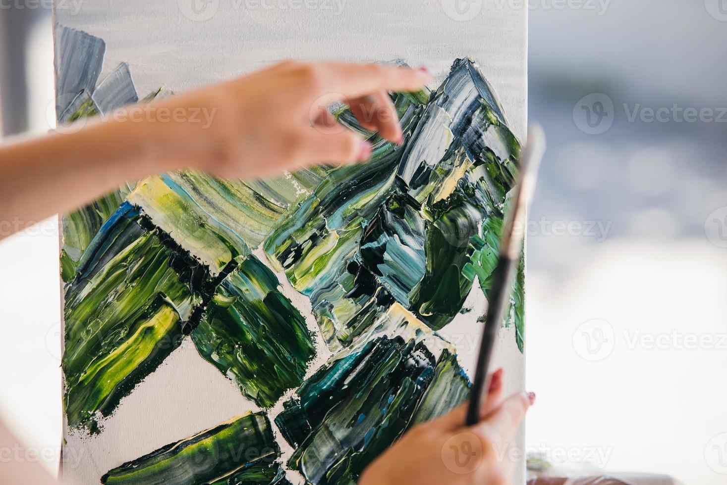 Young woman artist paints with a spatula on the canvas photo