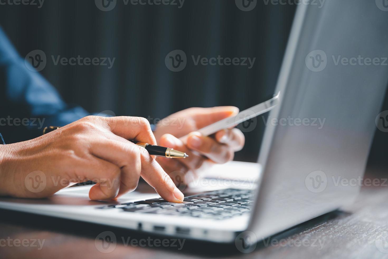 Closeup of businesswoman typing on laptop computer while sitting on table in office for design work, insert icons or business technology symbols. selective focus on hand. female online working on desk photo