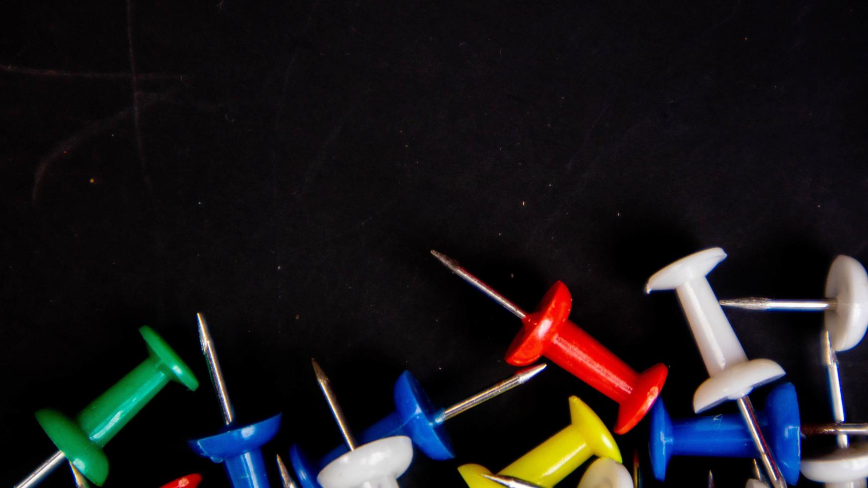 multicolored thumbtacks on a black background photo