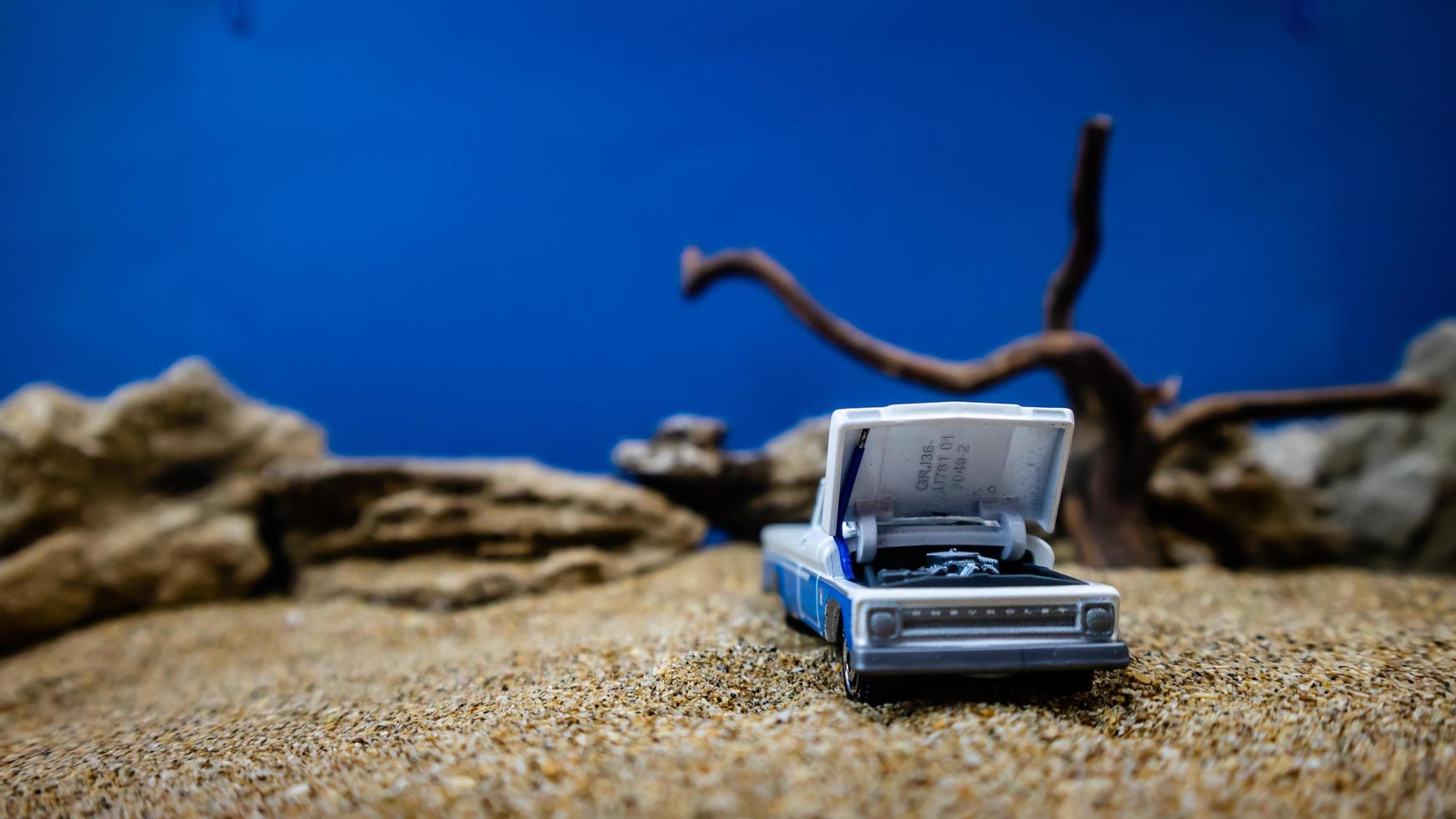 minahasa, Indonesia  January 2023, a toy car on the sand with a background of rocks and blue sky photo
