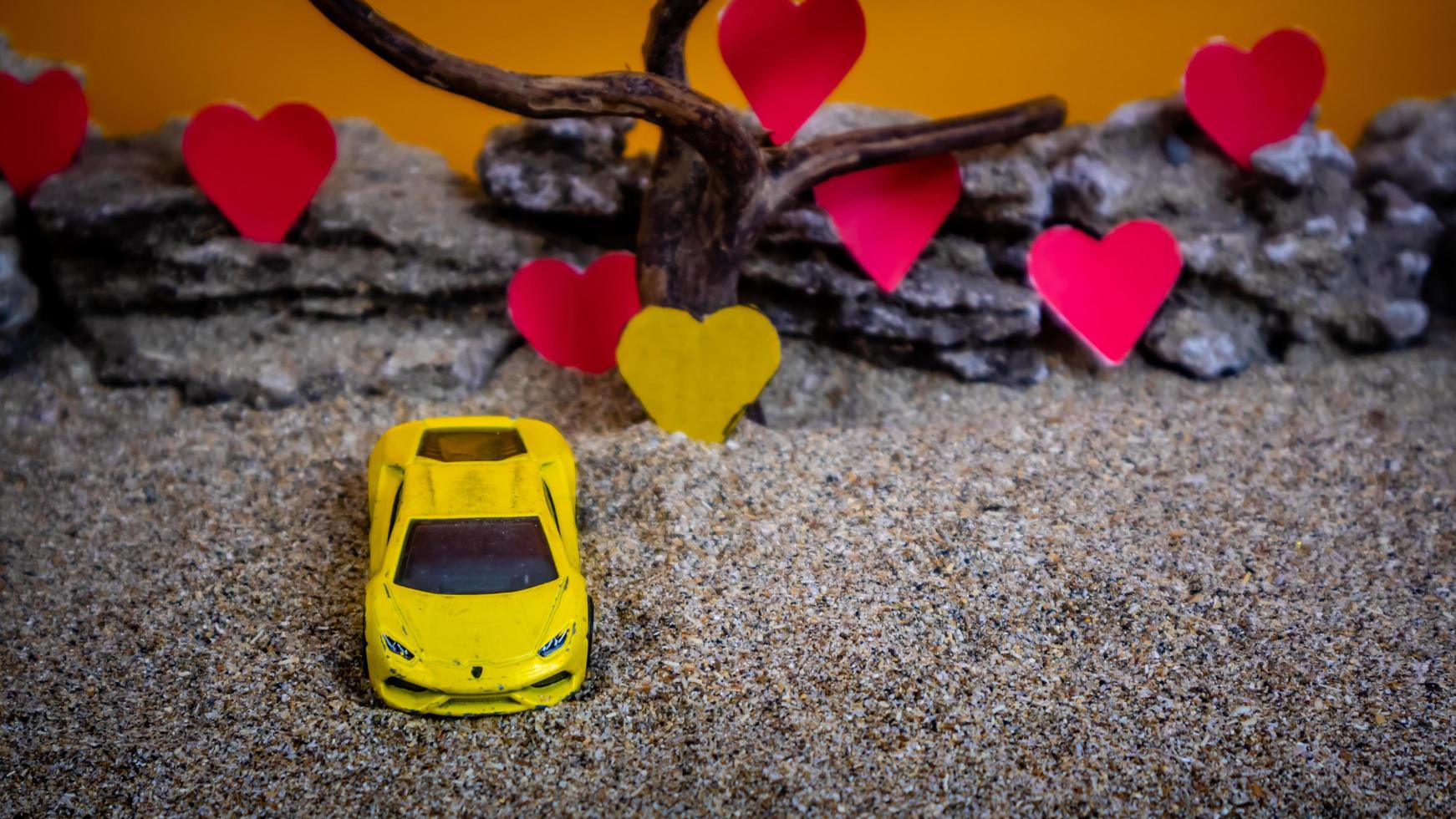 minahasa, indonesia diciembre de 2022, coche de juguete con fondo naranja degradado y corazón foto