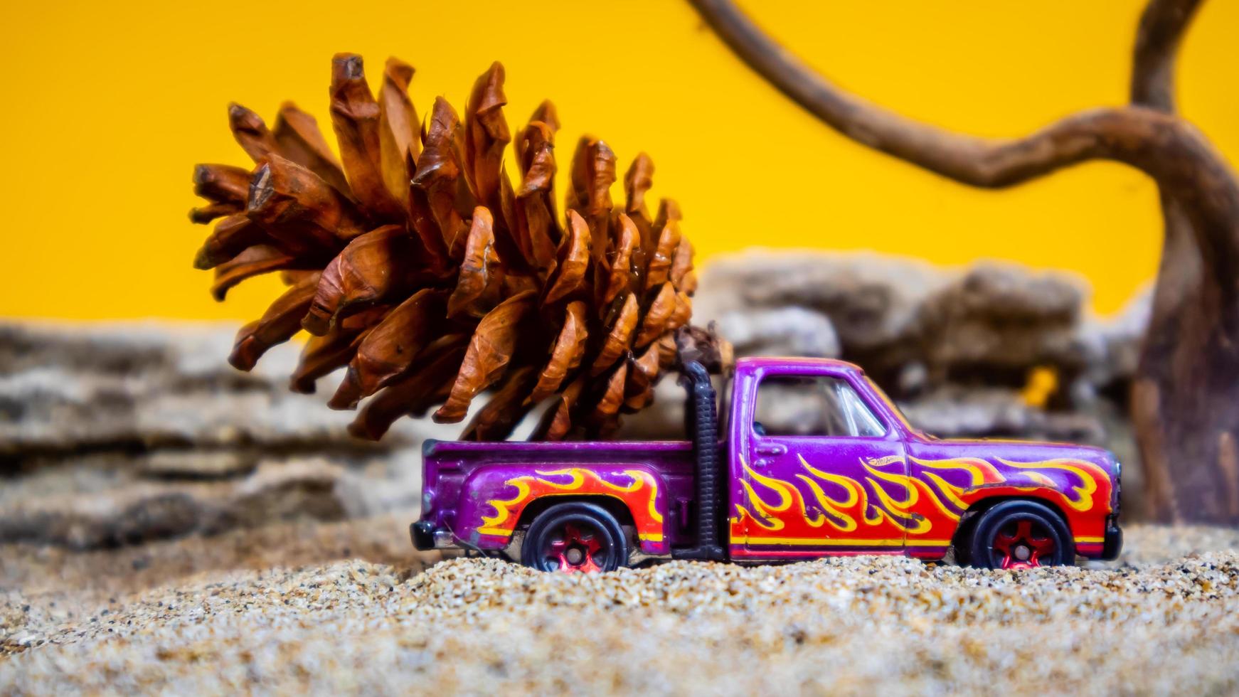 coche de juguete que transporta piñas sobre un fondo naranja foto