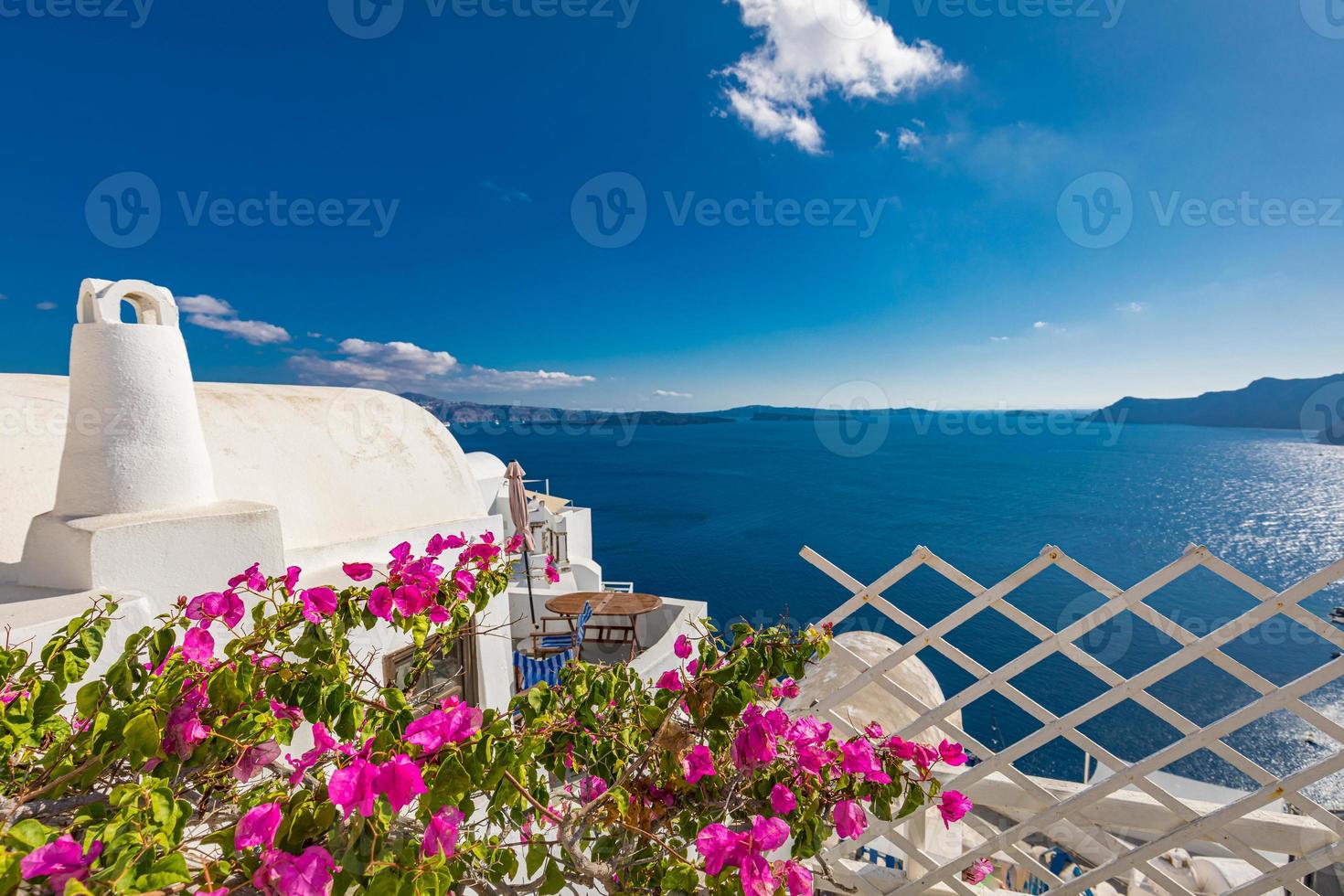 Santorini, Greece. Famous view of traditional white architecture Santorini landscape with flowers in foreground. Summer vacations background. Luxury travel tourism concept. Amazing summer destination photo
