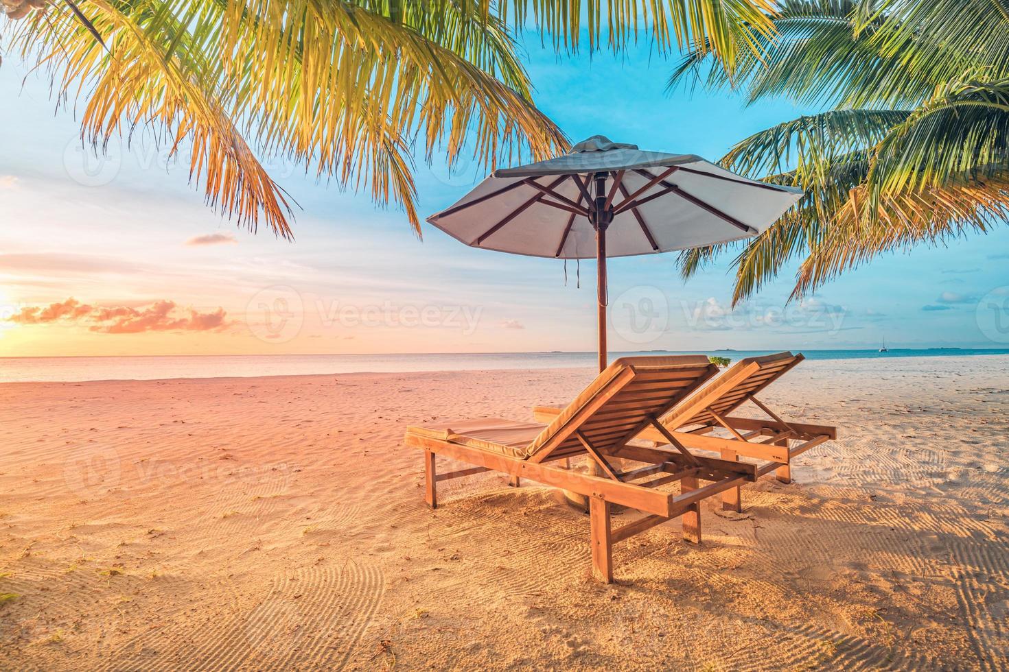 hermosa playa tropical de puesta de sol, tumbonas de pareja, sombrilla de tumbonas bajo palmera. arena blanca, vista al mar con horizonte, colorido cielo crepuscular, calma y relajación. hotel inspirador en la playa foto