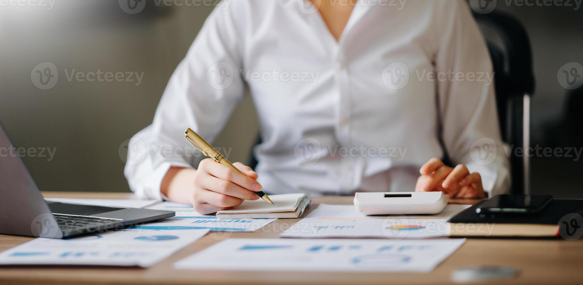 Women counting coins on calculator taking from the piggy bank. hand holding pen working on calculator to calculate on desk about cost at home office. photo