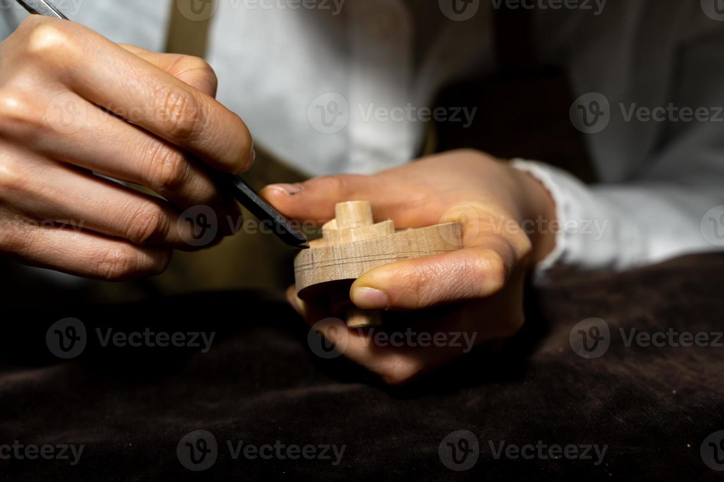 young Chinese female violin maker working with gouge to making a new violin photo