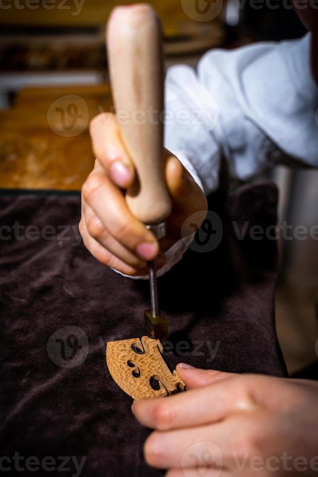 young Chinese woman violin maker signs the jumper of her violin with fire with her name photo