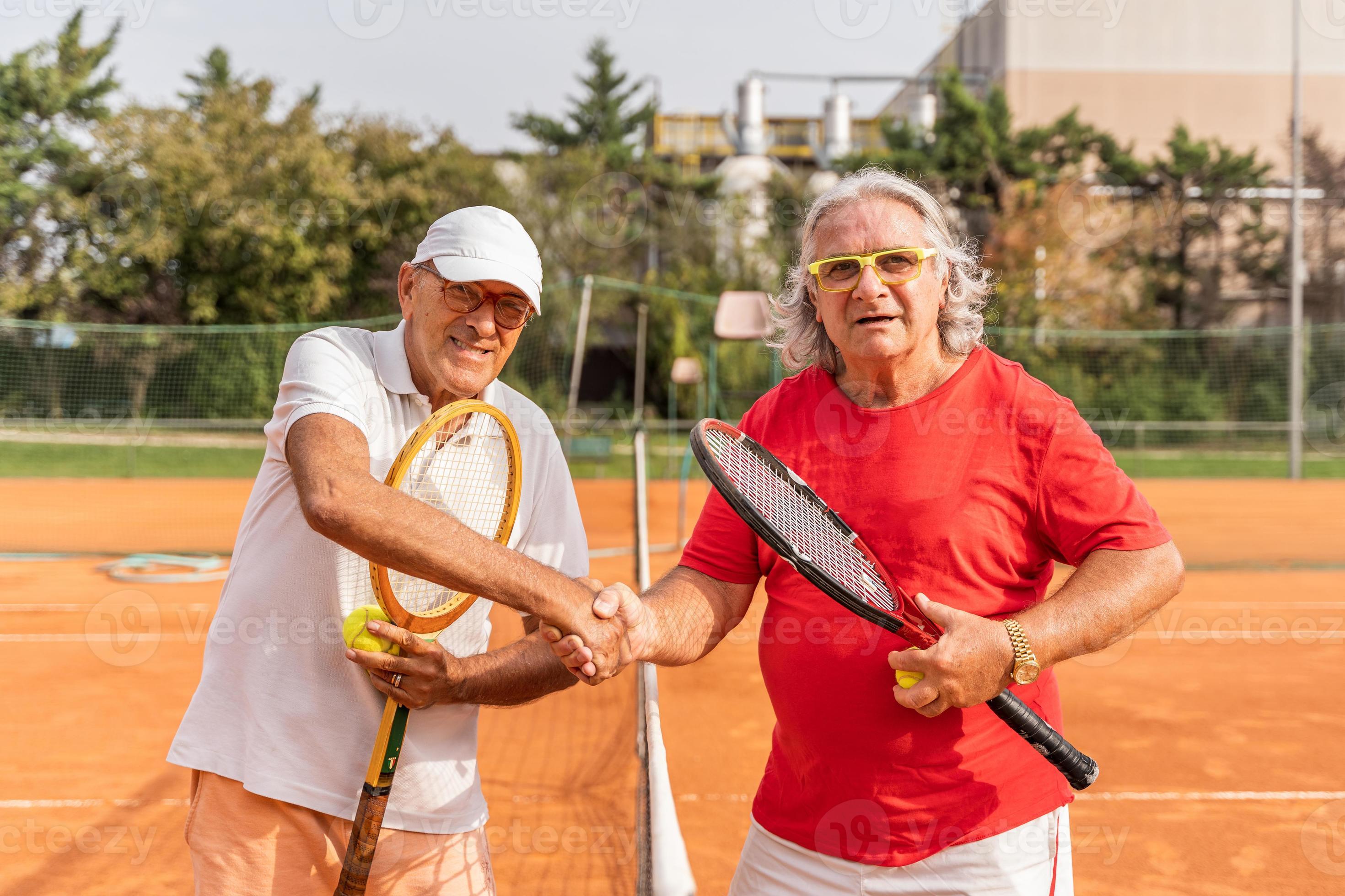 Portrait Of Two Senior Tennis Players Dressed In Sportswear Shaking