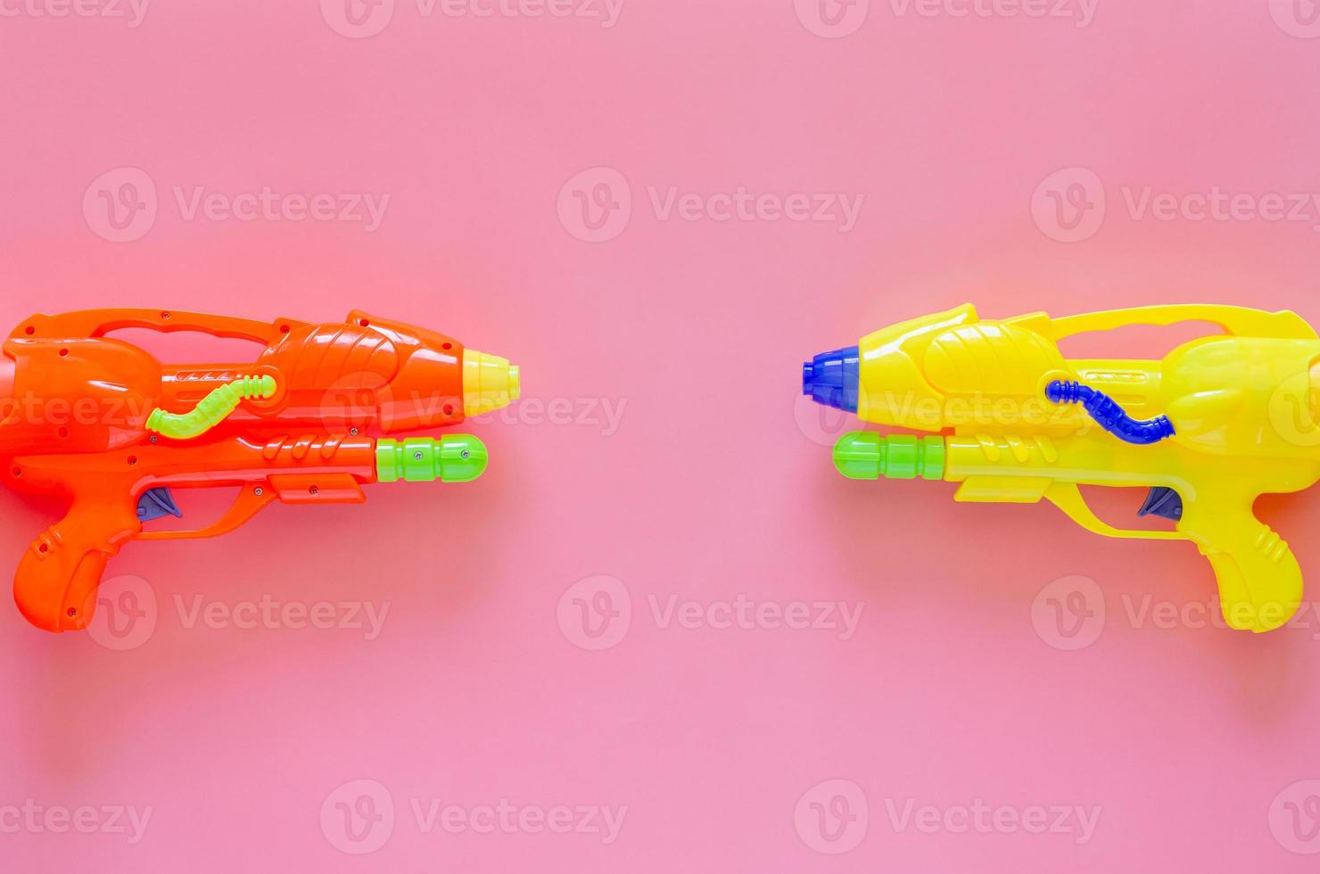 pistola de agua de plástico de colores para el festival de agua o songkran sobre fondo rosa. foto