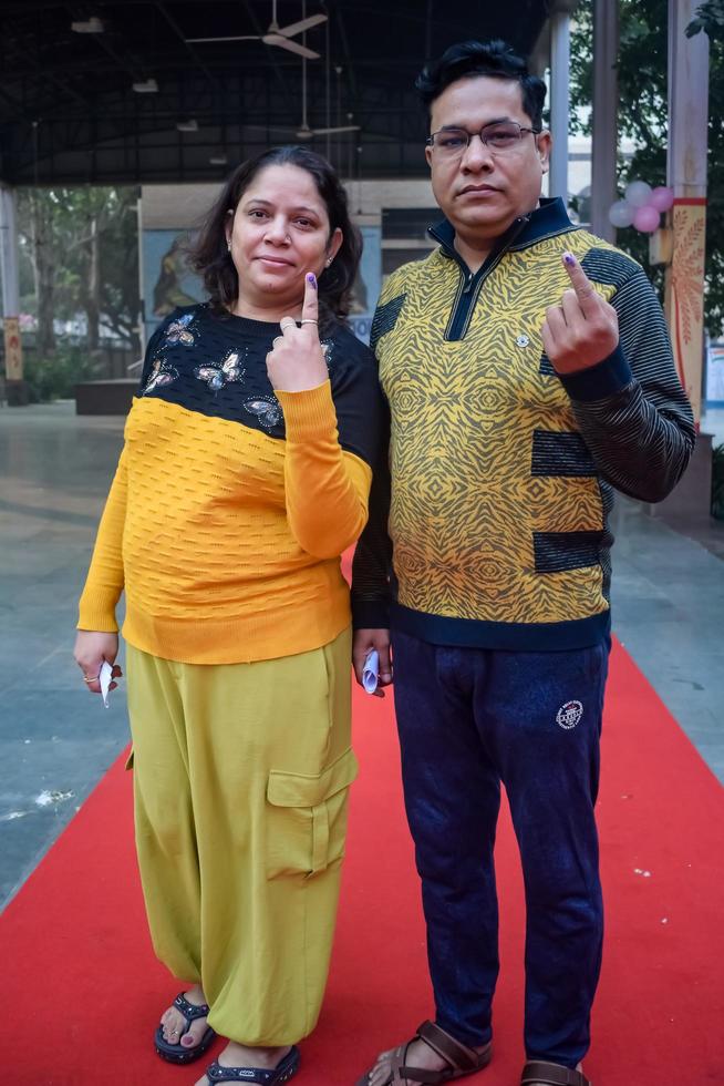 New Delhi, India - December 04 2022 - Unidentified people showing their ink-marked fingers after casting votes in front of polling booth of east Delhi area for MCD local body Elections 2022 photo