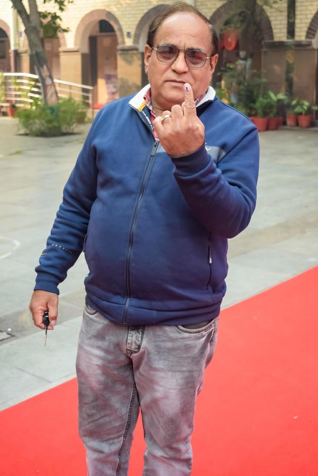 New Delhi, India - December 04 2022 - Unidentified people showing their ink-marked fingers after casting votes in front of polling booth of east Delhi area for MCD local body Elections 2022 photo