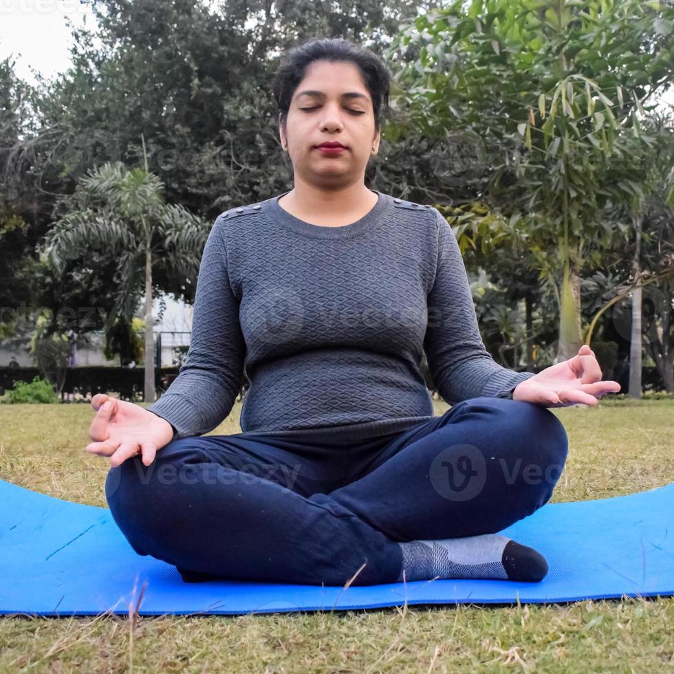 Young Indian woman practicing yoga outdoor in a park. Beautiful girl practice basic yoga pose. Calmness and relax, female happiness. Basic Yoga poses outdoor photo