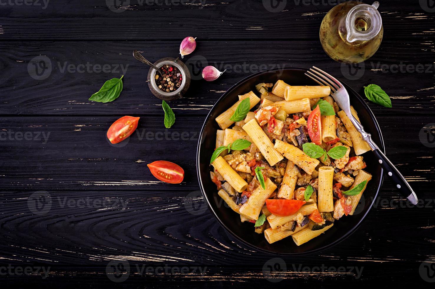 Rigatoni pasta with chicken meat, eggplant in tomato sauce in bowl. Italian cuisine. Top view. Copy space photo