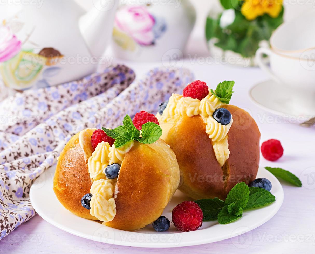 Rum baba decorated with whipped cream and fresh raspberry, blueberry. Savarin with rum, cream and berries. Italian cuisine photo