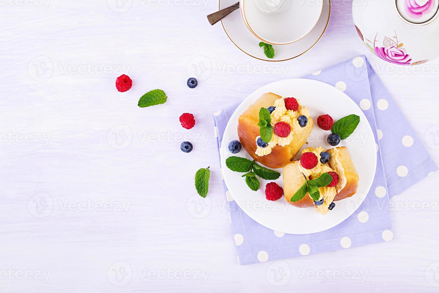 ron baba decorado con crema batida y frambuesa fresca, arándano. savarín con ron, nata y frutos del bosque. cocina italiana. vista superior foto