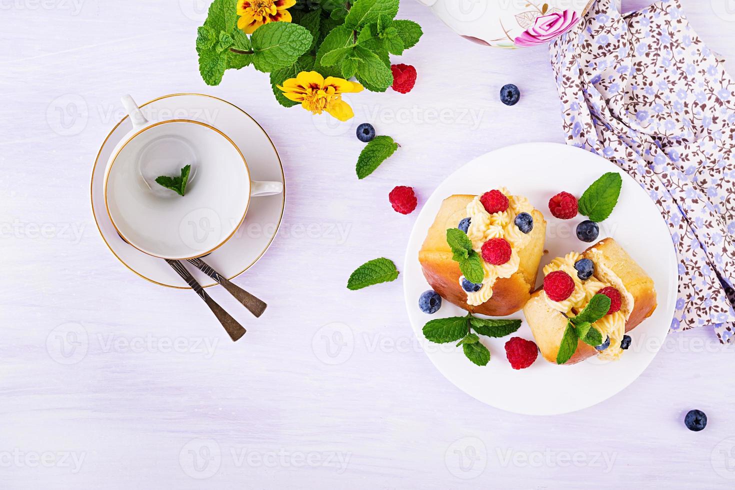 ron baba decorado con crema batida y frambuesa fresca, arándano. savarín con ron, nata y frutos del bosque. cocina italiana. vista superior foto