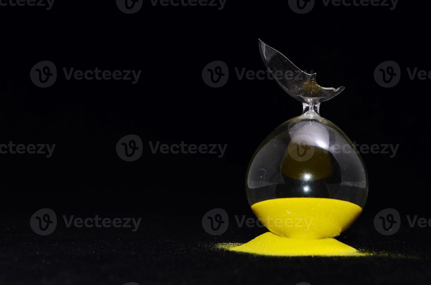 Broken hourglass on black background photo