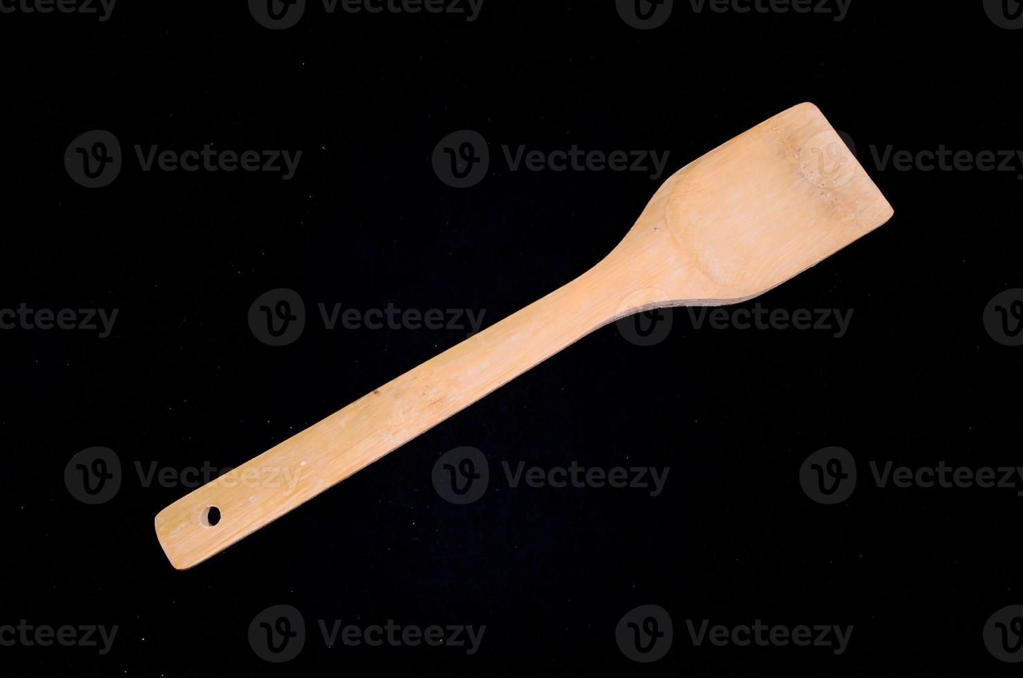 Wooden spoon on black background photo