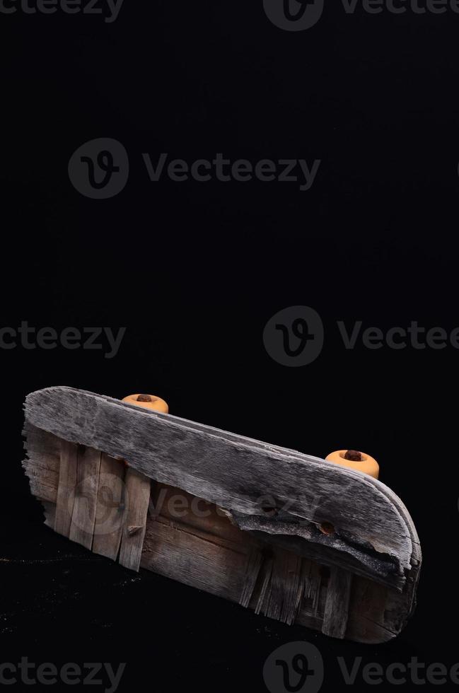 Old skateboard on black background photo