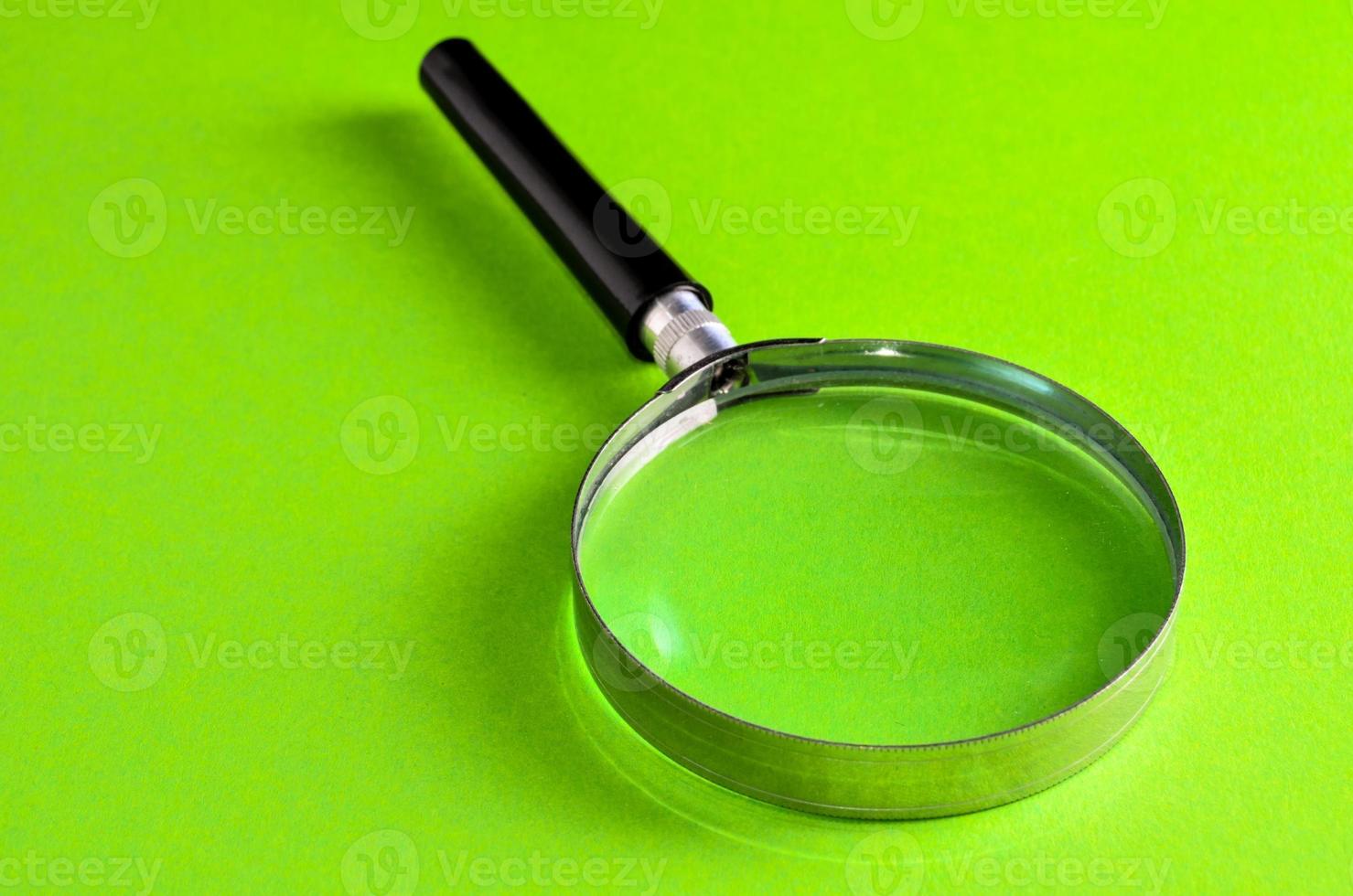 Magnifying glass on green background photo