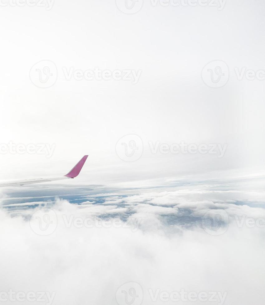 Airplane wing flying above a dramatic sky with white clouds viewed from a high altitude. Viewed from the airplane window. photo