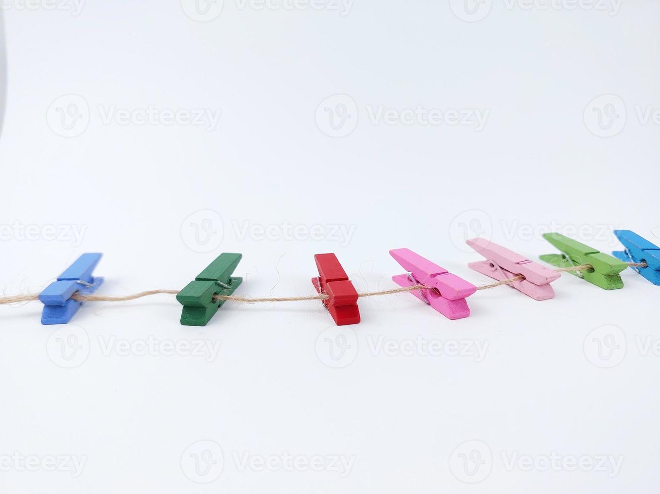 una fila de clips de madera de colores del arco iris sobre un fondo blanco foto