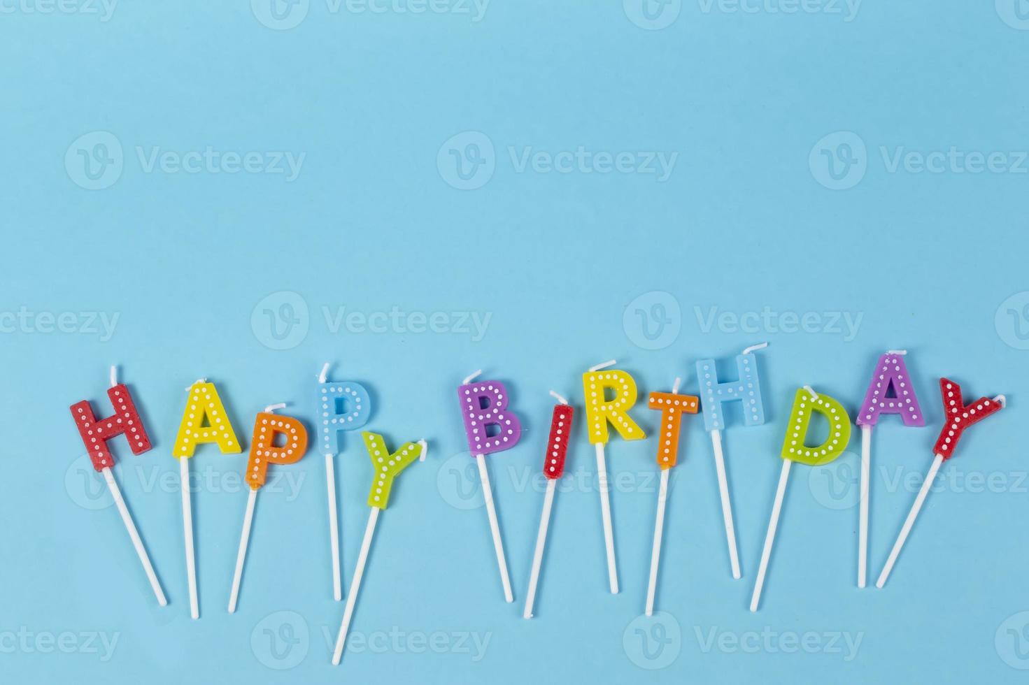 Colorful candles in letters with Happy Birthda  lettering isolated on blue background photo