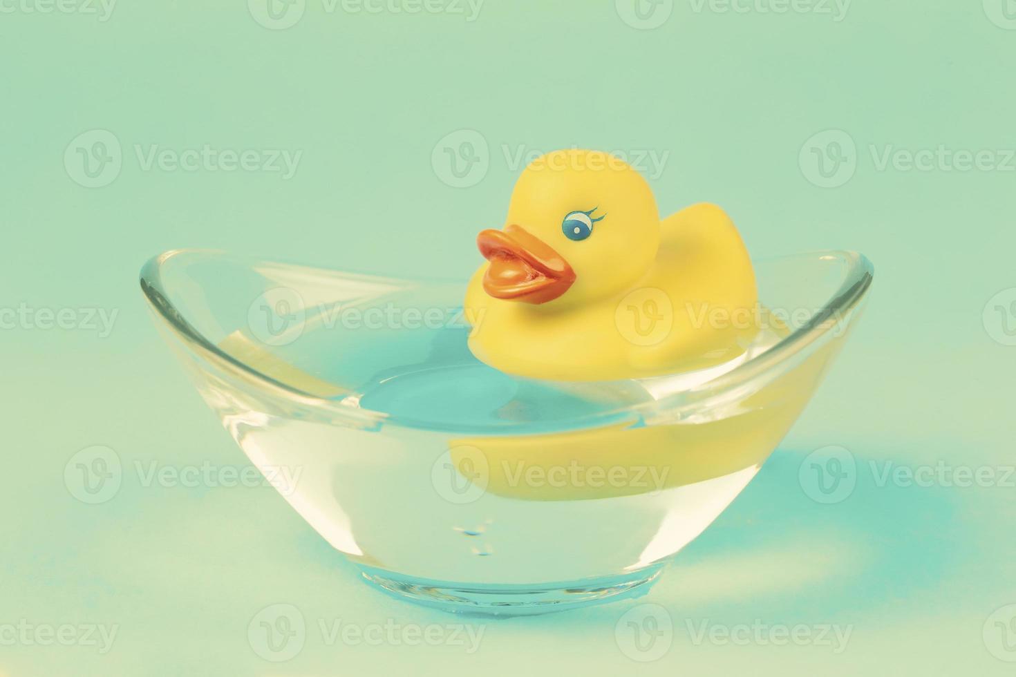 A yellow rubber duck swims in a bath against an emerald background. photo