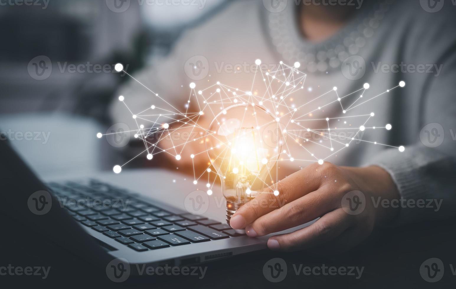 Businesswoman hand holding light bulb with icons and working on the desk, Creativity and innovation are keys to success.Concept of new idea and innovation with energy and power , working at home, photo