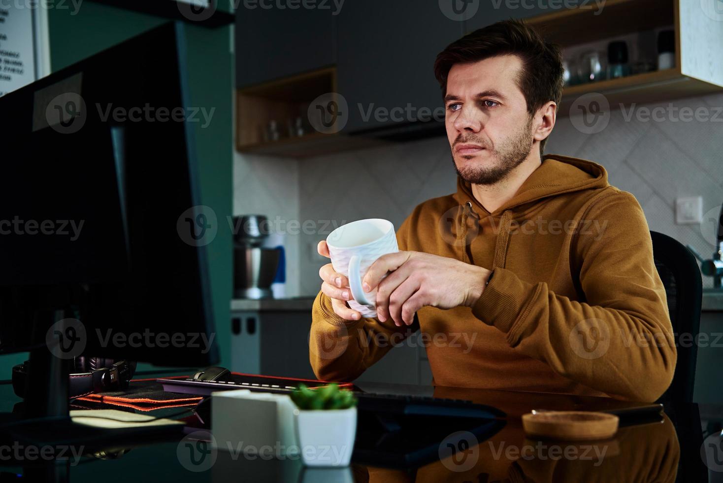 Tired man works late at workplace, use computer photo