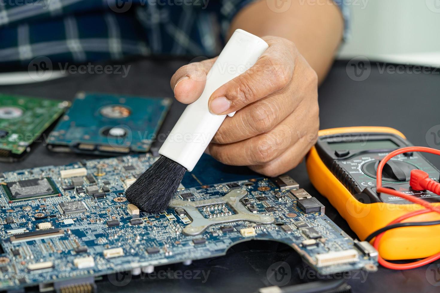 Technician use brush and air blower ball to clean dust in circuit board computer. Repair upgrade and maintenance technology. photo