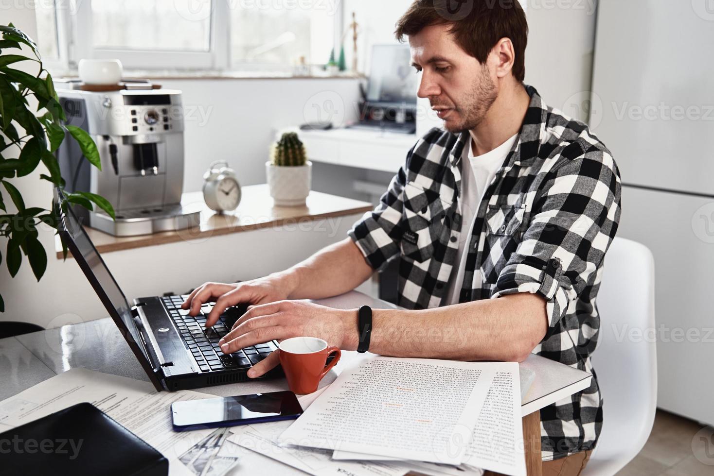 Man works at home office with laptop and documents photo