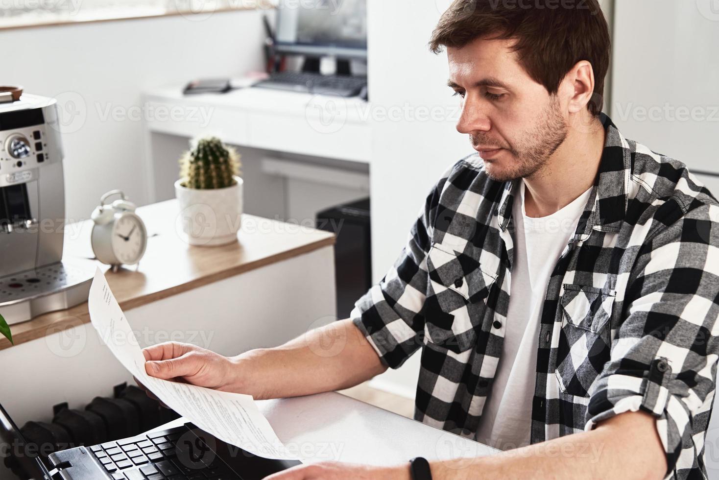 Man works at home office with laptop and documents photo