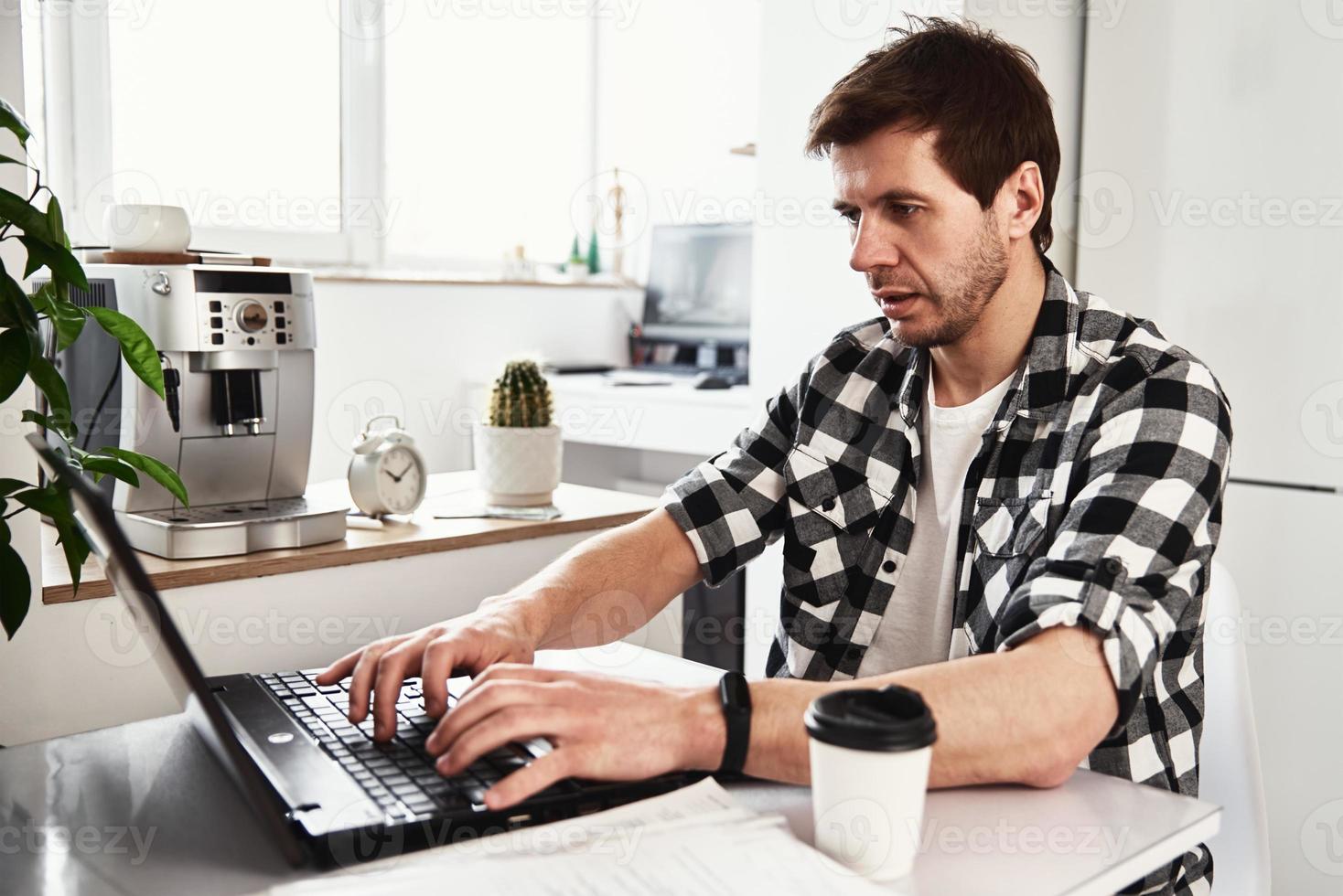 Man works at home office with laptop and documents photo