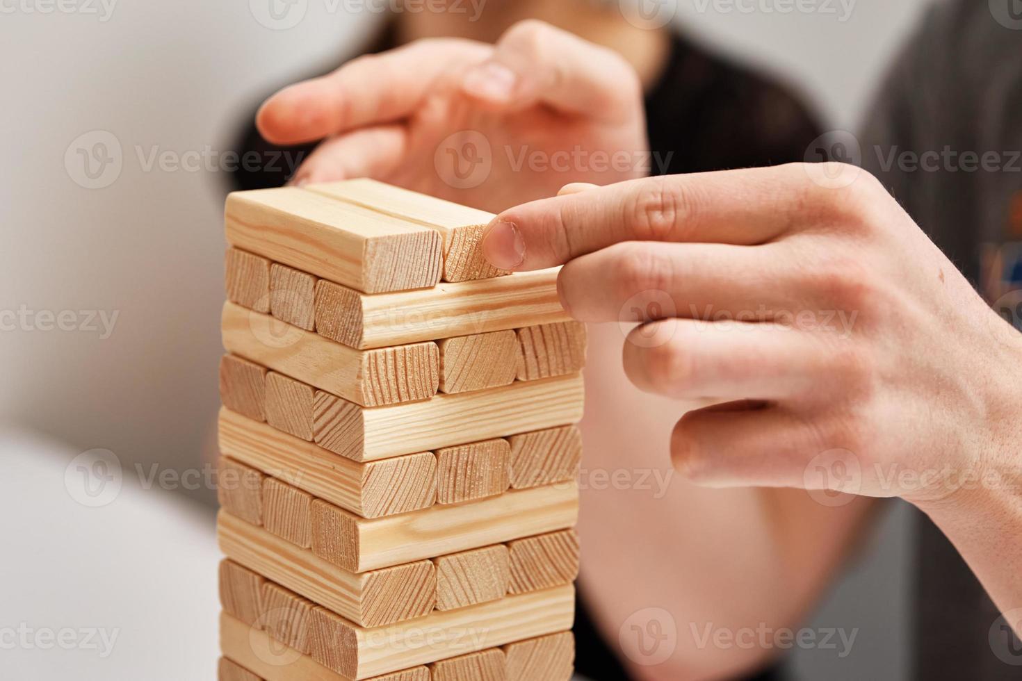 juego de mesa familiar. las manos toman un bloque de madera de la torre. foto