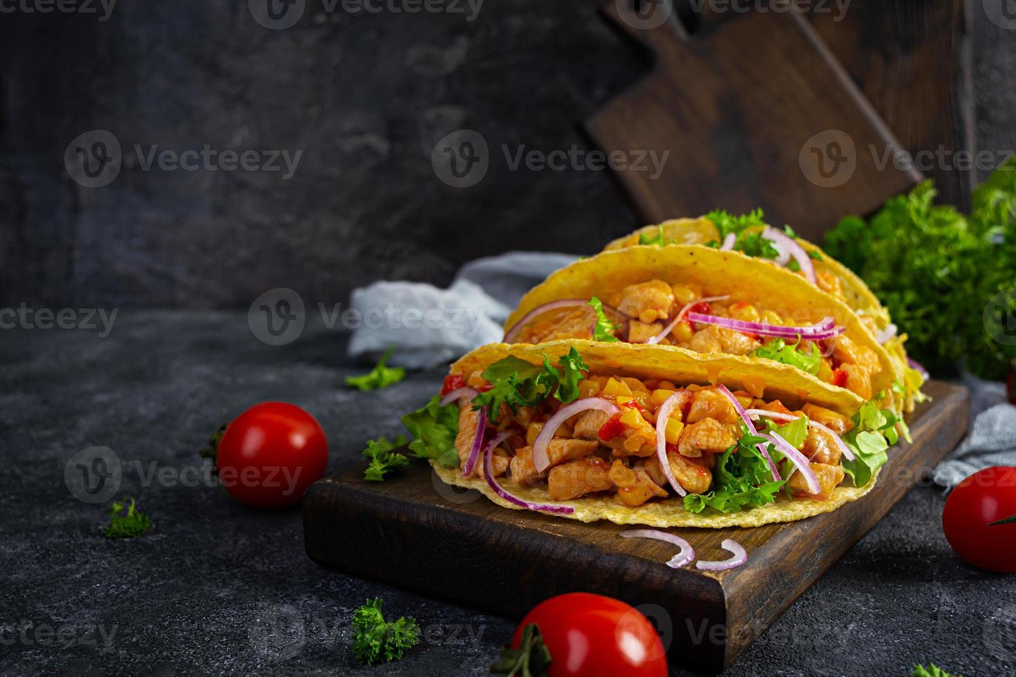 tacos mexicanos con tortilla de maíz. tortilla con carne de pollo, maíz, lechuga y cebolla foto