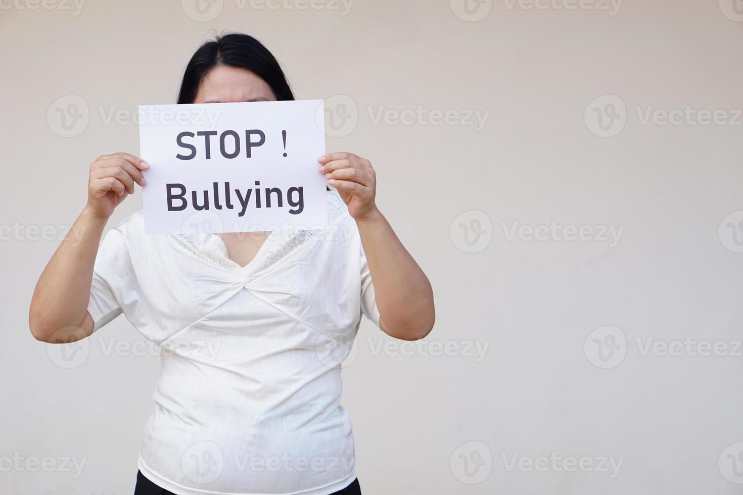 Closeup woman holds paper with text  STOP Bullying. Concept, campaign for anti bullying, body shaming or parody of others physical appearance. Stop violence. photo