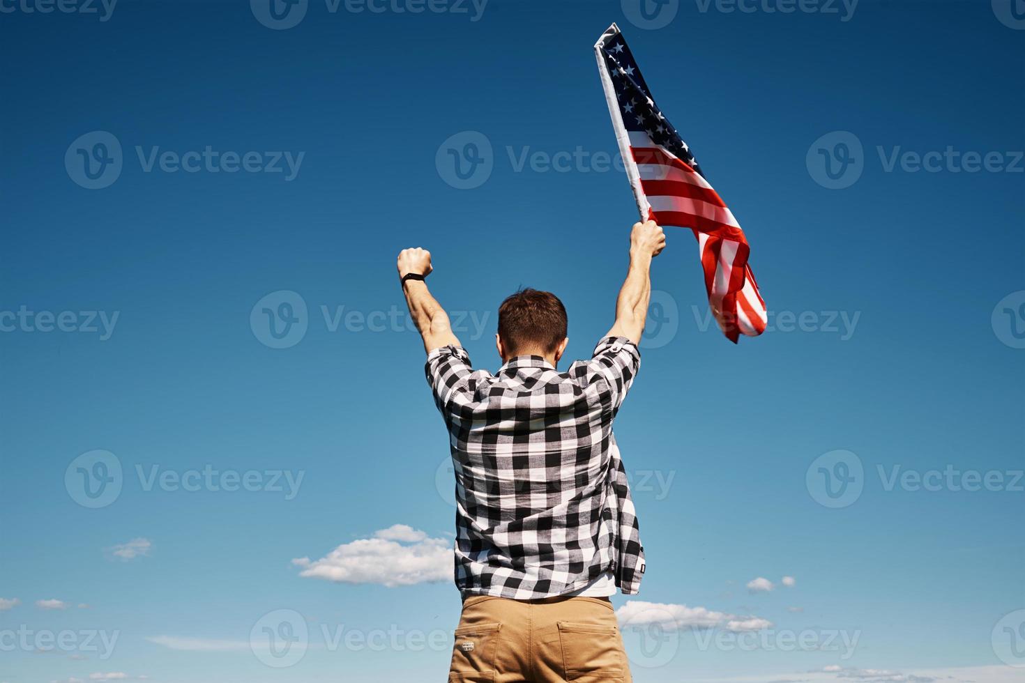 Man holds usa national flag against blue sky photo