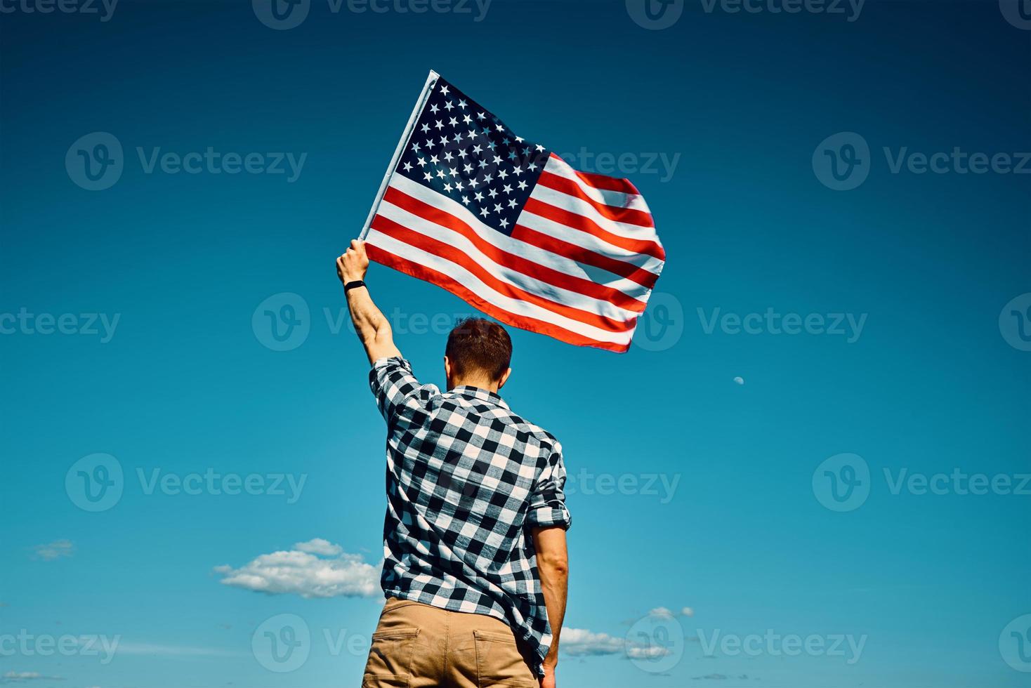 Man holds usa national flag against blue sky photo