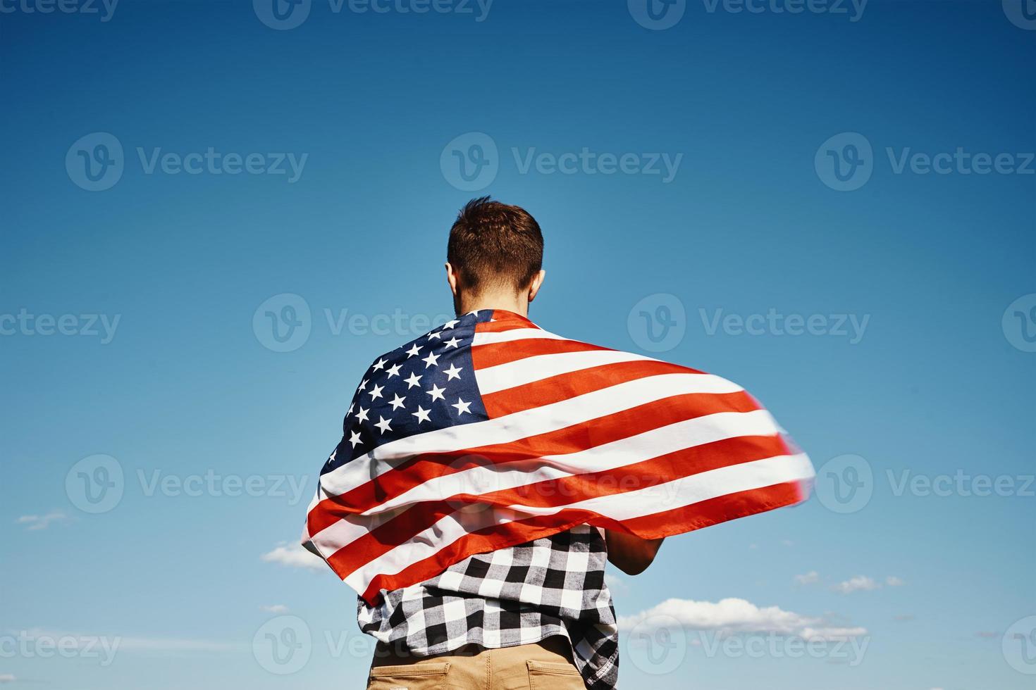 Man holds usa national flag against blue sky photo