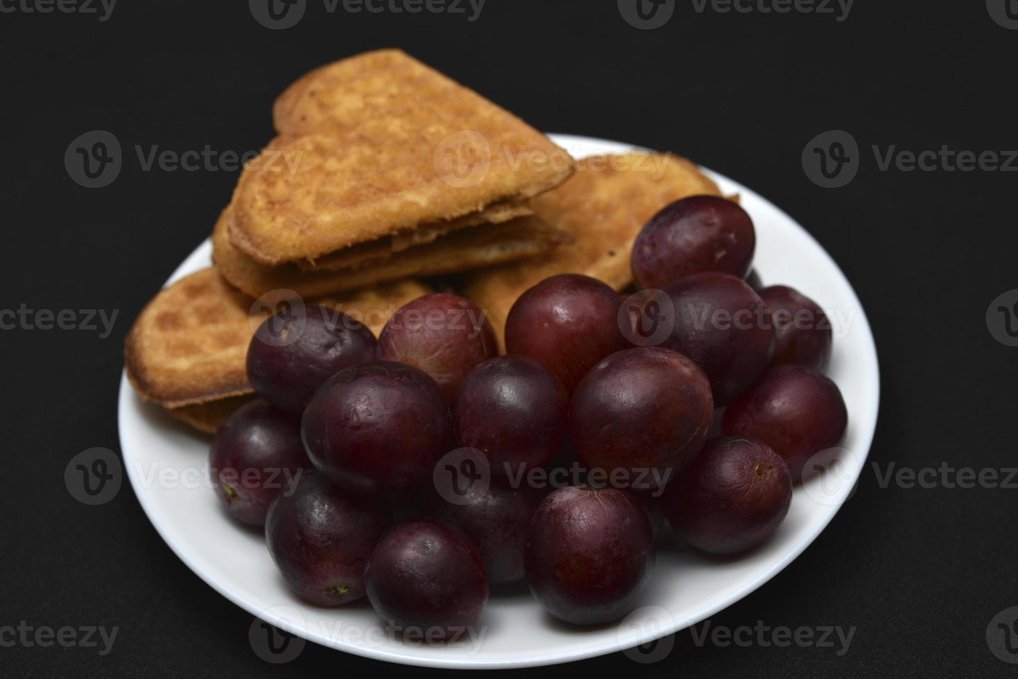 Delicious waffles and grapes on a plate. A sweet breakfast of waffles and red grapes. Heart-shaped waffles. photo