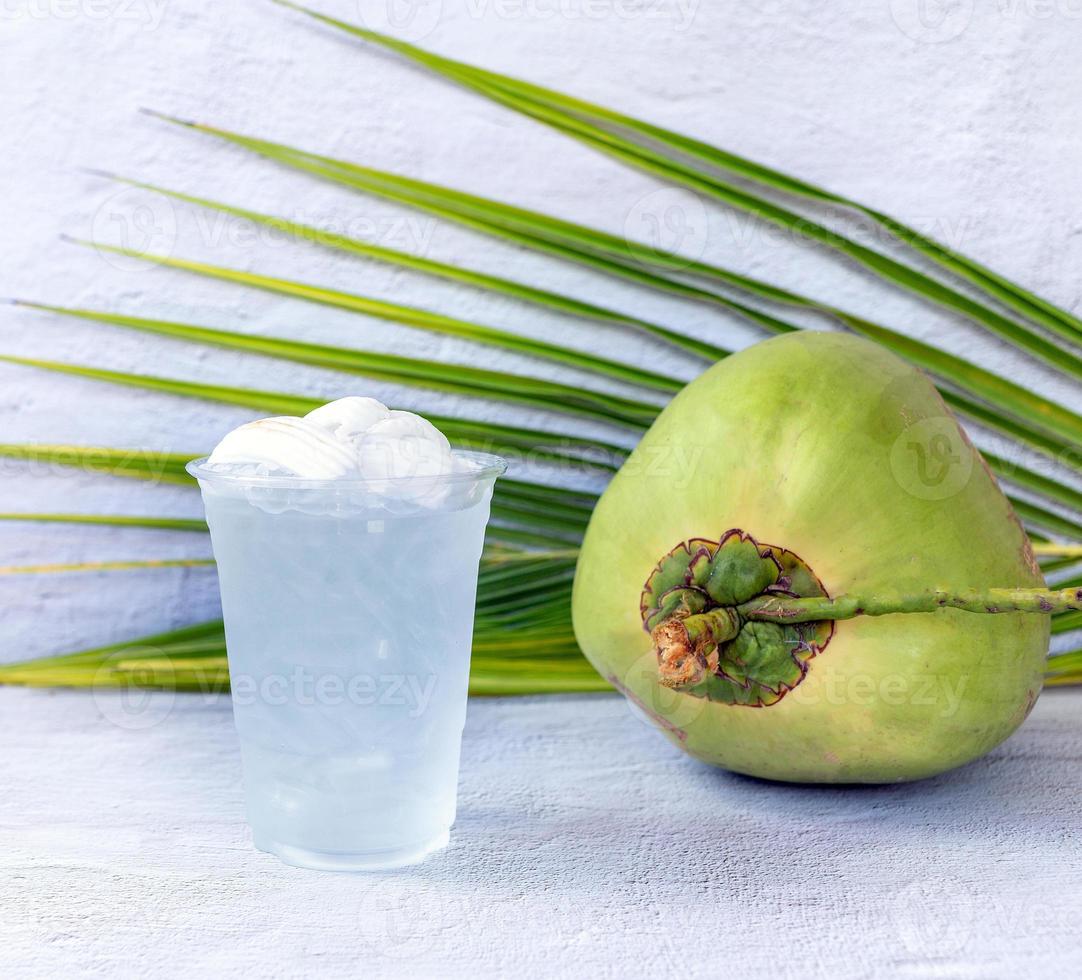 Ice coconut water drink in a plastic glass and coconut on white background photo