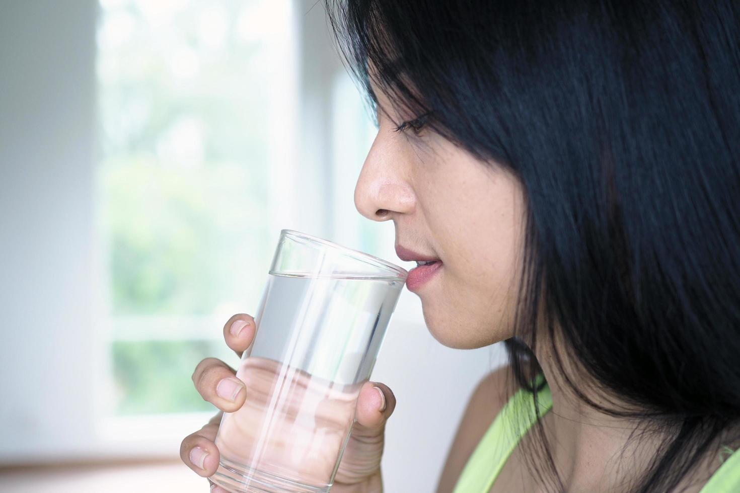 una hermosa mujer asiática está feliz de beber agua. para una buena salud y piel foto