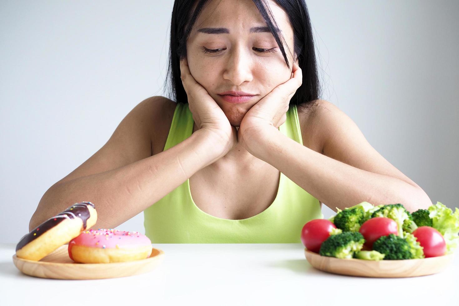 Asian beautiful women choose between vegetables and donuts. lose weight photo